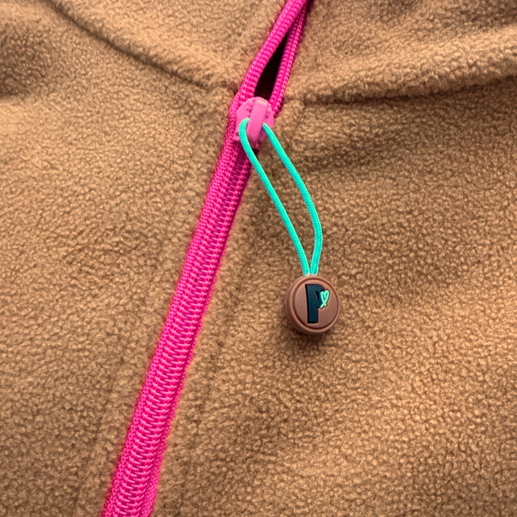 Close-up of the fuchsia zipper and turquoise Peek Breeze pull on the Toffee fleece