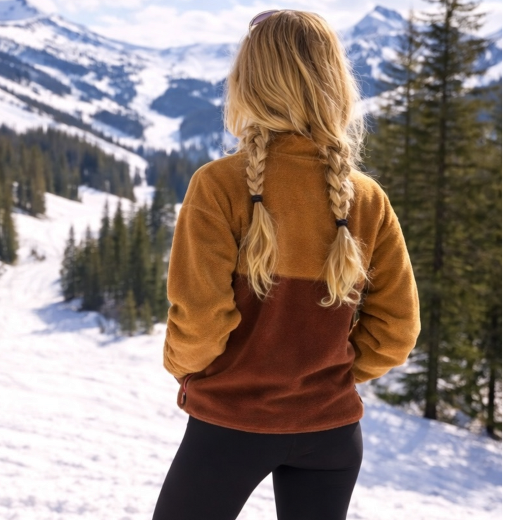Back view of the Toffee caramel and brown fleece pullover in a snowy mountain setting