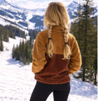 Back view of the Toffee caramel and brown fleece pullover in a snowy mountain setting