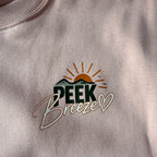 Close-up of the Peek Breeze chest logo on the Coastal crewneck