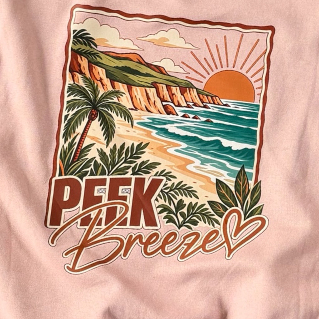 Close-up of the tropical beach print on the back of the pale pink Coastal crewneck
