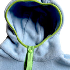 Close-up of the Seaside fleece dress hood in light blue with navy lining, lime trim and snap button