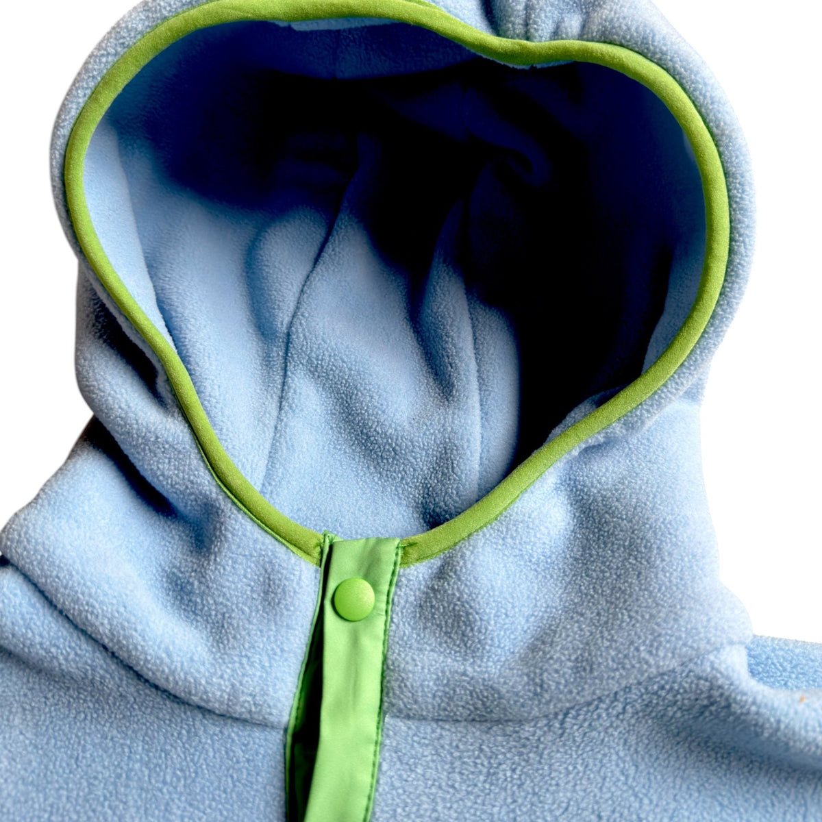 Close-up of the Seaside fleece dress hood in light blue with navy lining, lime trim and snap button