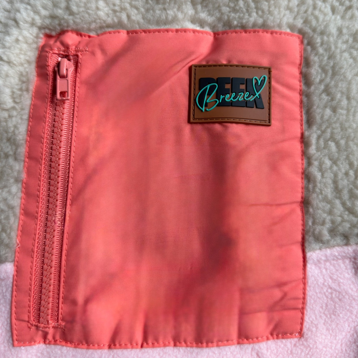 Close-up of the pink zippered pocket and Peek Breeze label on the sherpa of the Peachy dress
