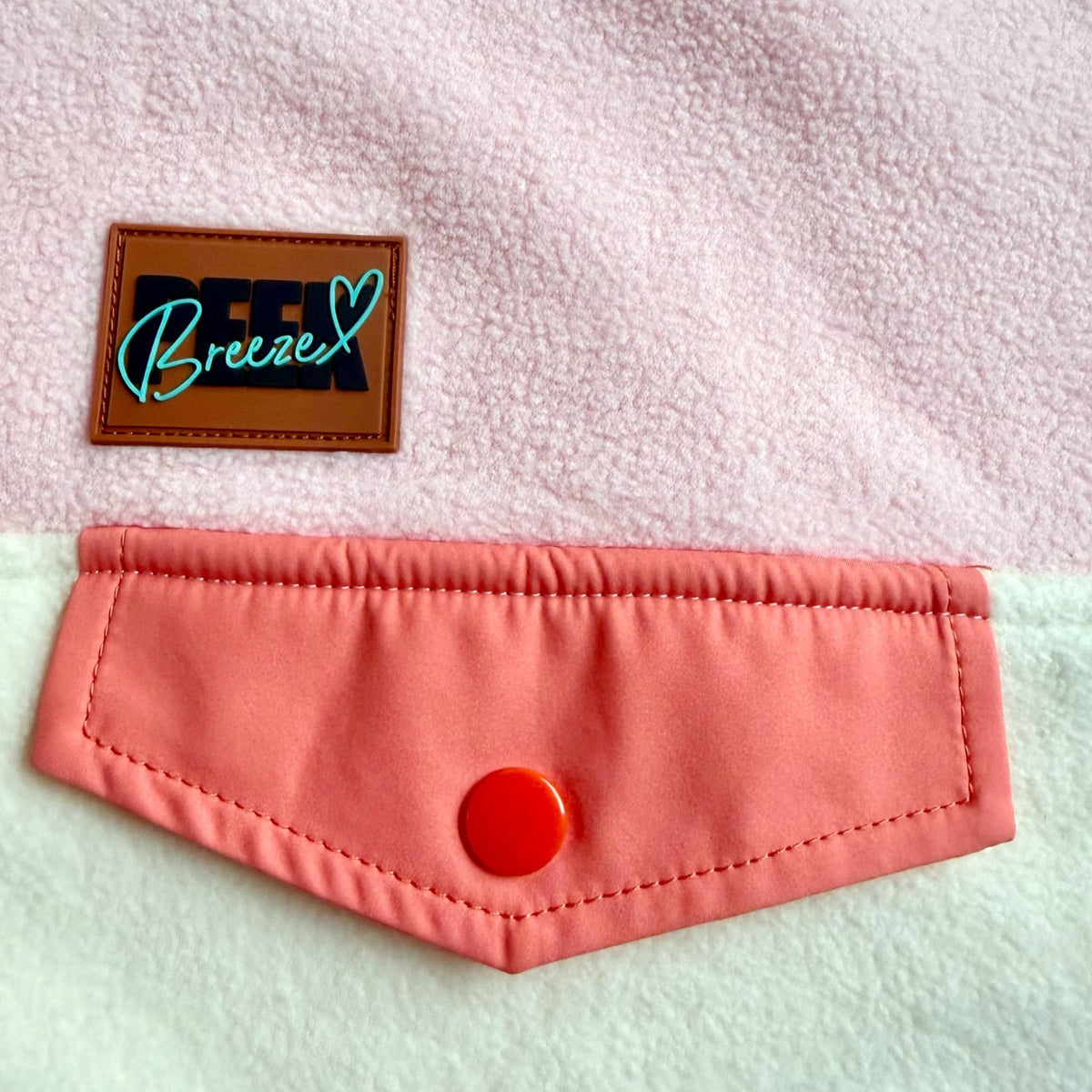 Close-up of the coral chest pocket and Peek Breeze label on the Blush fleece dress