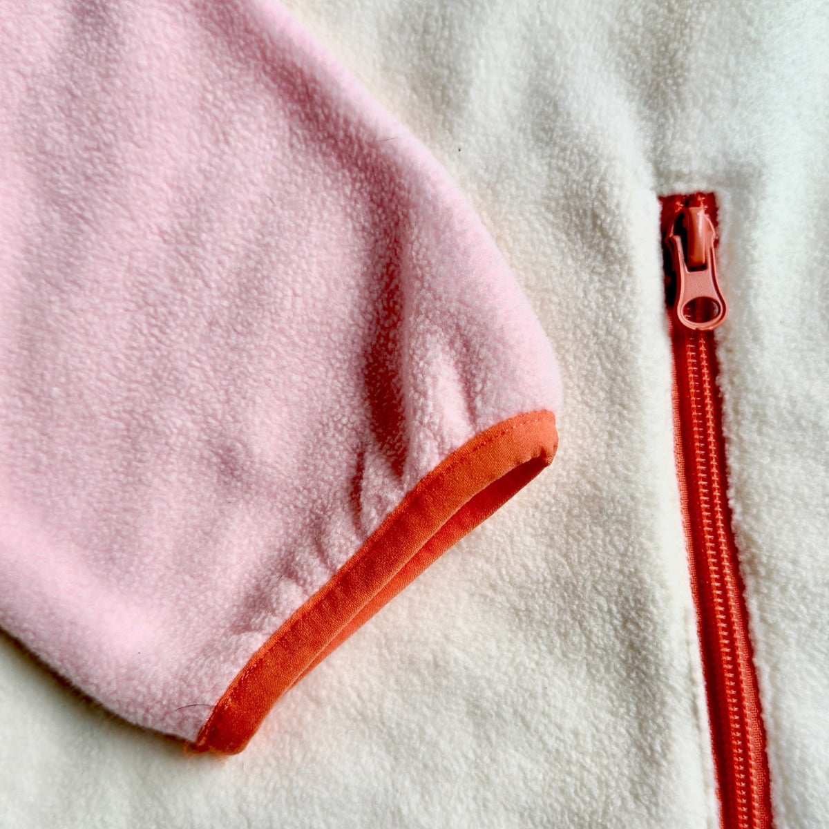 Close-up of the coral snap pocket and brown logo label on the Blush fleece dress