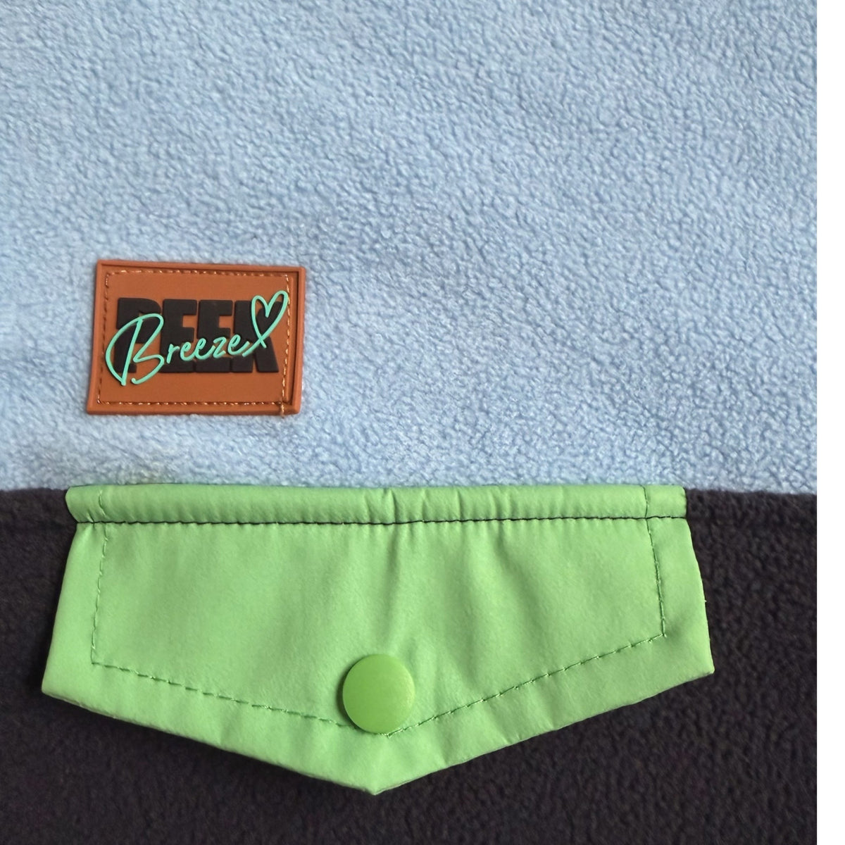 Close-up of the lime-green snap chest pocket and Peek Breeze label on the Seaside fleece dress