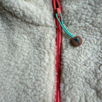 Close-up of the beige sherpa with coral zipper and turquoise logo pull on the Peachy dress