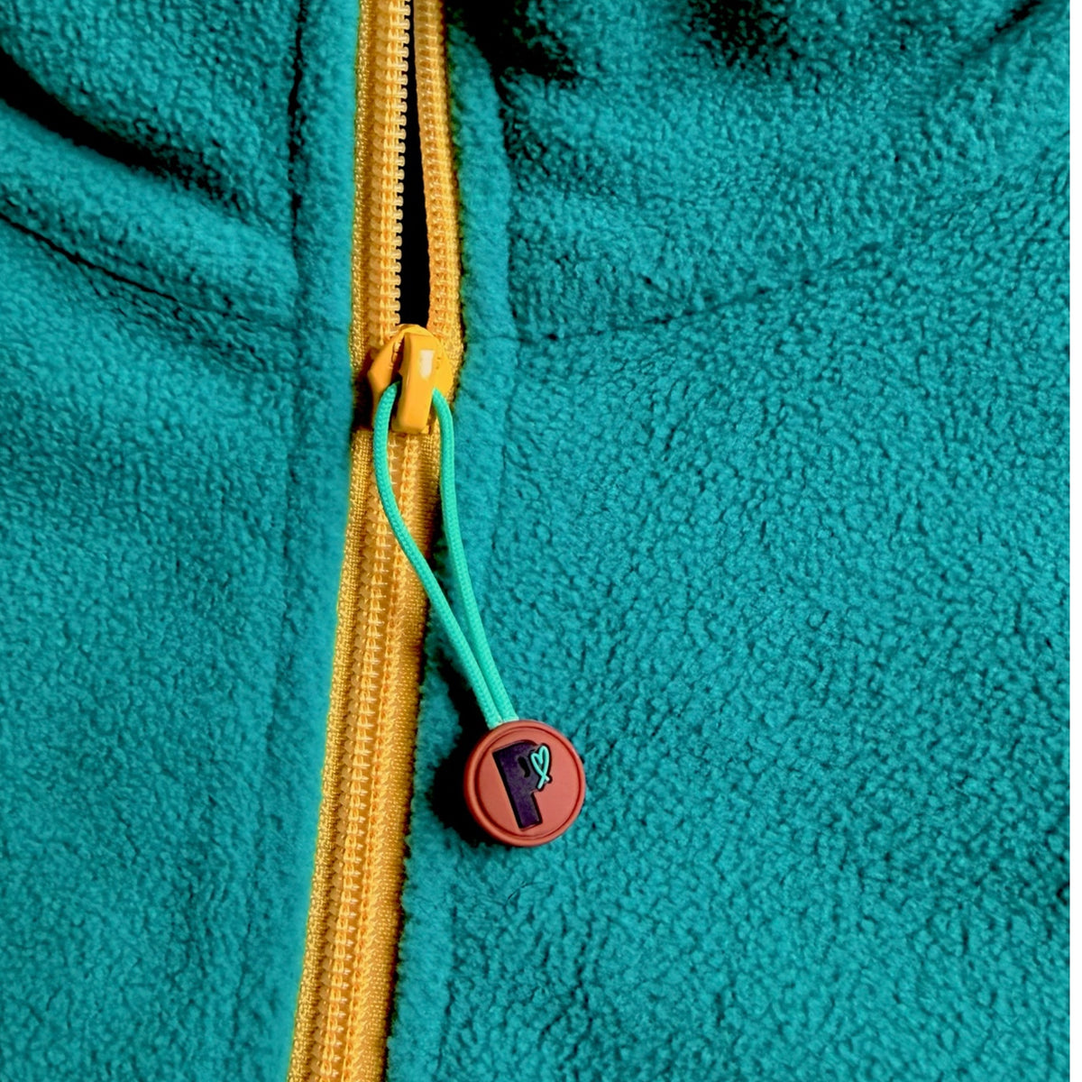 Close-up of the yellow quarter-zip and Peek Breeze logo zipper pull on forest green fleece