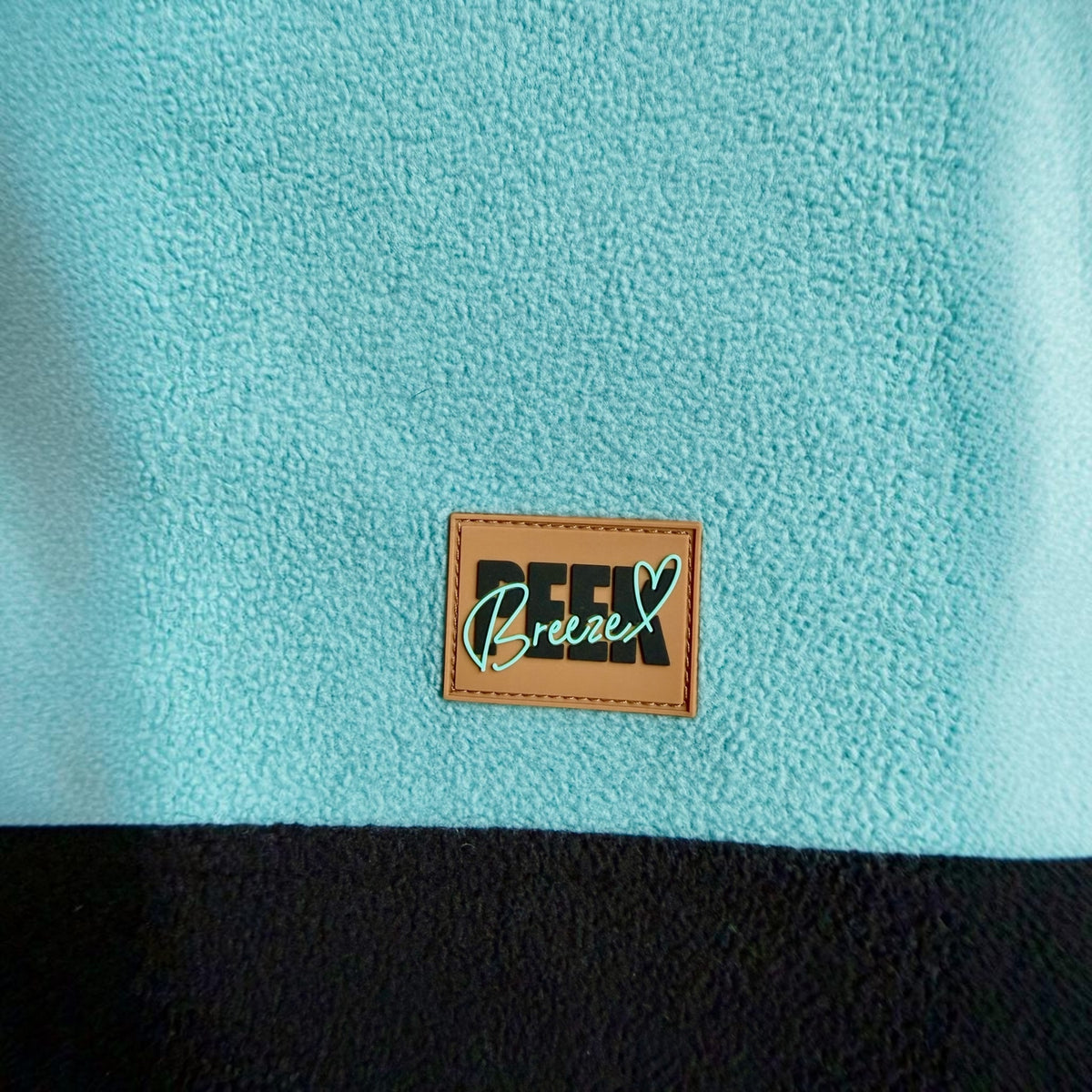 Peek Breeze logo patch on sage green fleece above the black panel