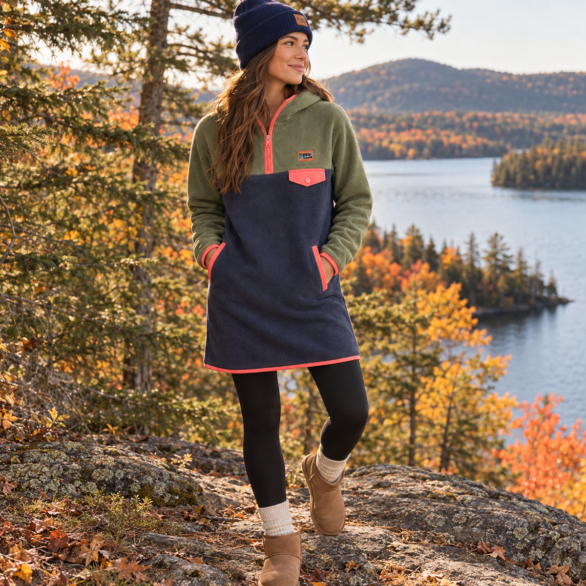 Woman wearing the Retro fleece dress with black leggings, boots, wool socks and a navy beanie by a lake in fall