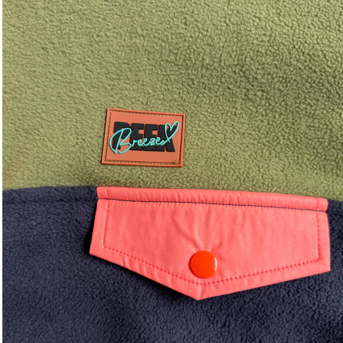 Close-up of the coral flap chest pocket and Peek Breeze label on the Retro fleece dress