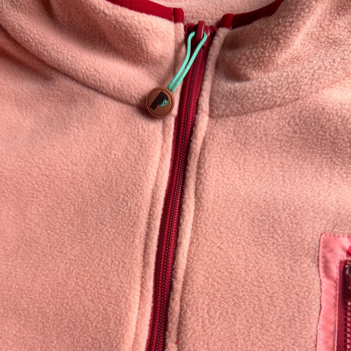 Close-up of the stand collar with zipper and turquoise logo pull on the Rosie fleece dress